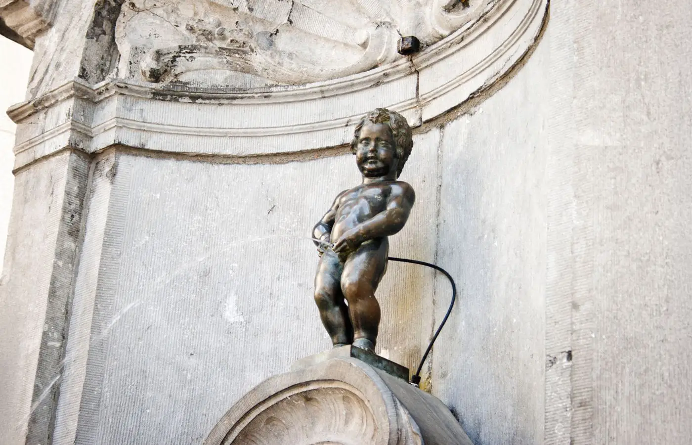 Statue emblématique du Manneken-Pis à Bruxelles, célèbre fontaine représentant un petit garçon urinant, symbole de l'humour et des traditions bruxelloises.