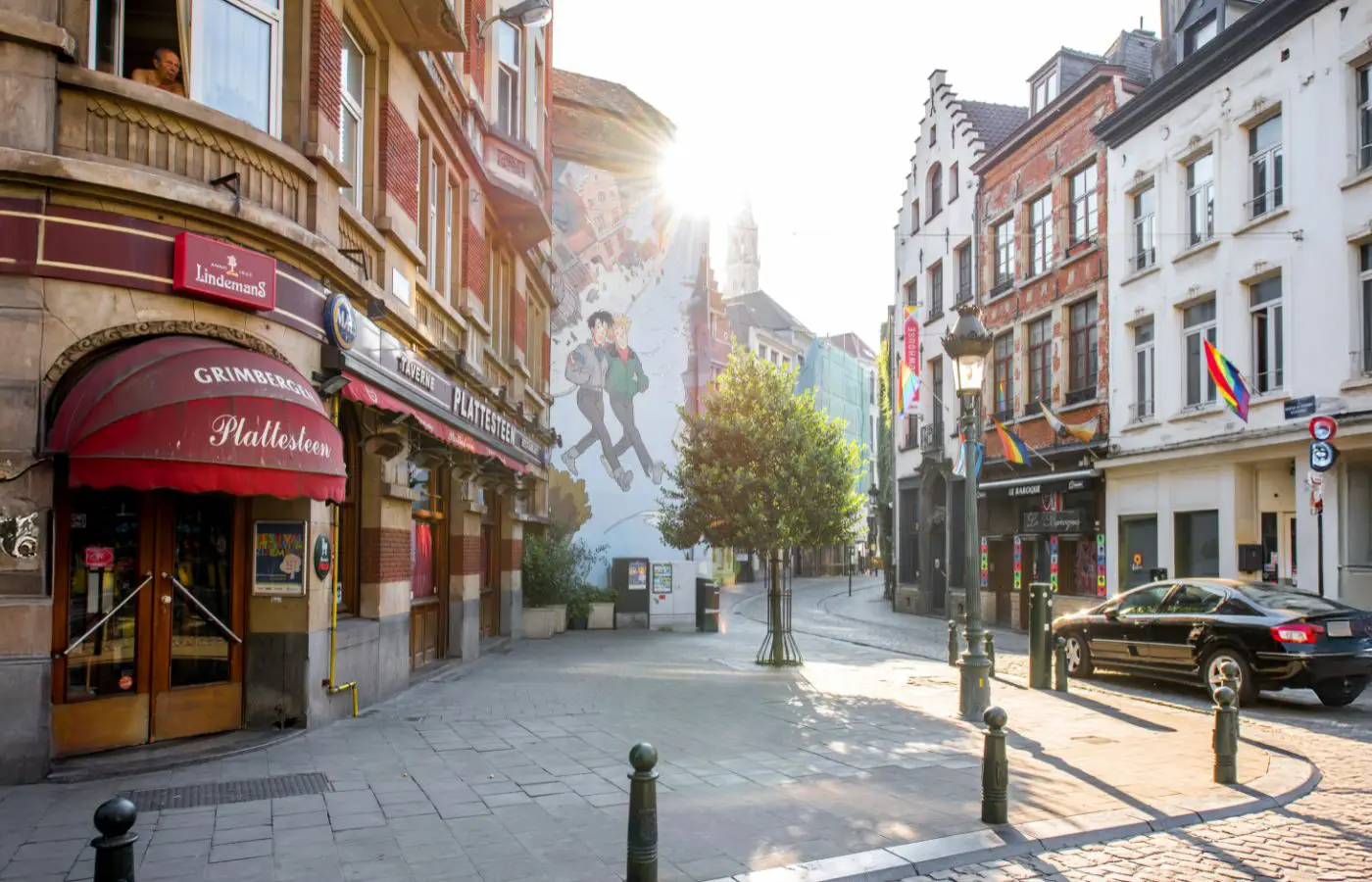 Rue de Bruxelles avec une fresque de bande dessinée représentant Tintin, Milou et le Capitaine Haddock, entourée de bâtiments historiques et baignée par une lumière ensoleillée.